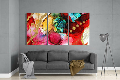Three colorful glass art panels with red, pink, gold, turquoise, and yellow hues displayed above gray sofa in modern living room.