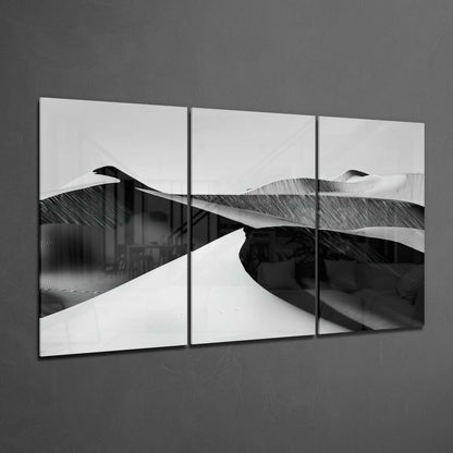 Three-panel black and white desert glass art displaying sand dunes with stark contrasts, mounted on gray wall.