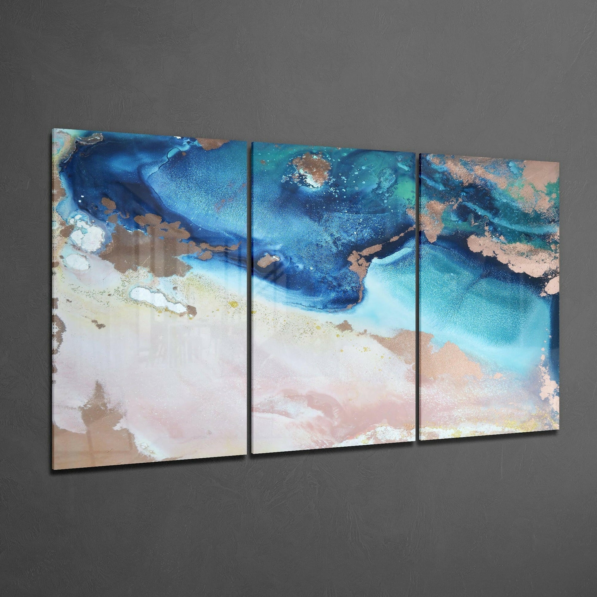 Three-panel triptych glass art displaying aerial coastal view with deep blue water, turquoise shallows, sandy beach, and rust-colored rock formations.