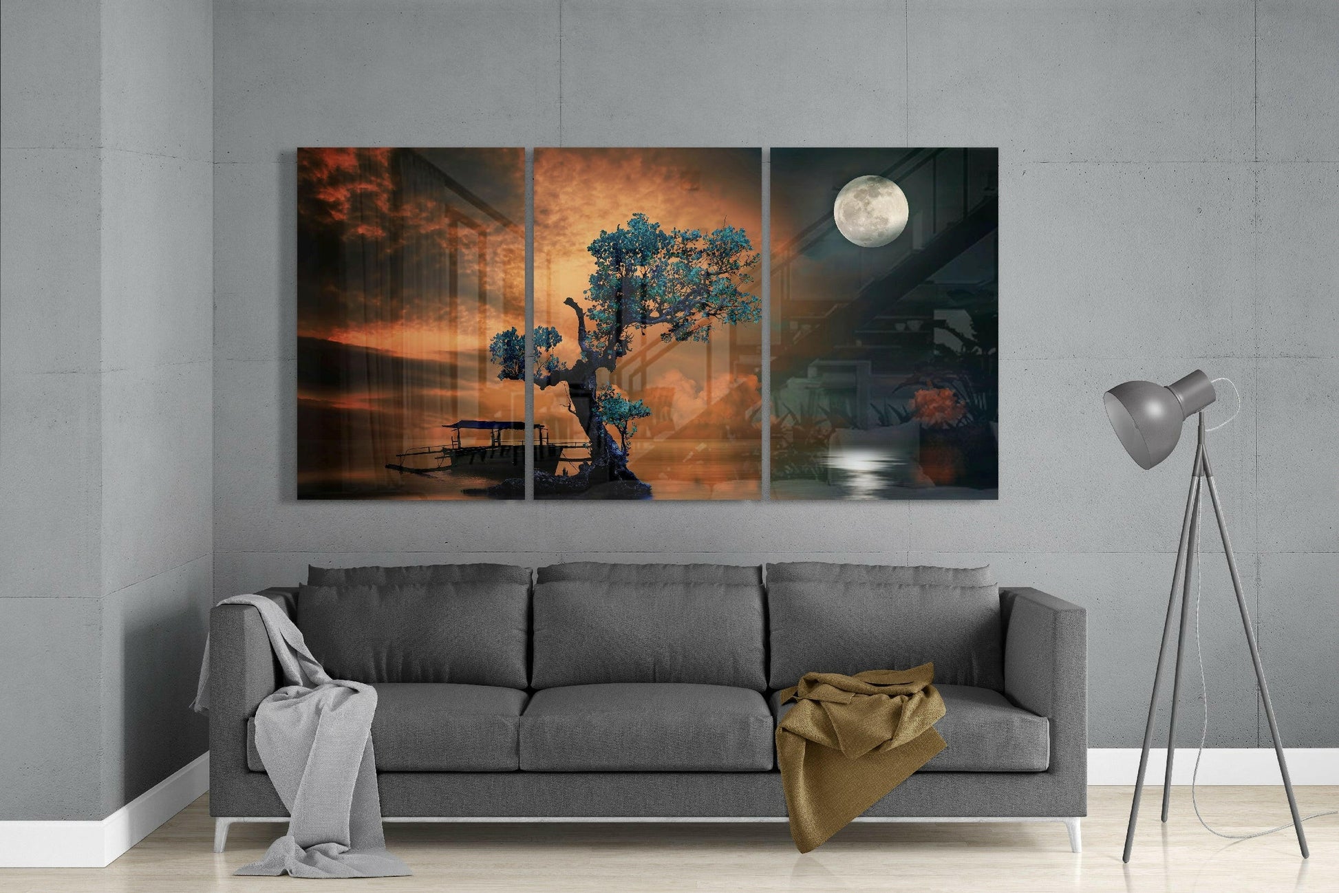 Three-panel glass wall art depicting a mystical bonsai tree with blue foliage against warm orange and cool moonlit backgrounds, displayed above a gray sofa.