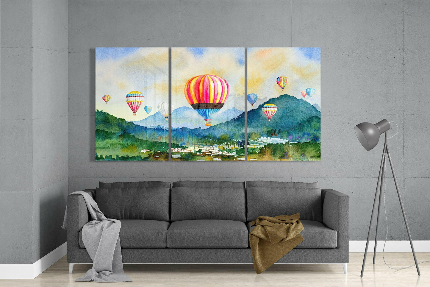 Three-panel watercolor glass art depicting colorful hot air balloons floating over green mountains and a town valley.