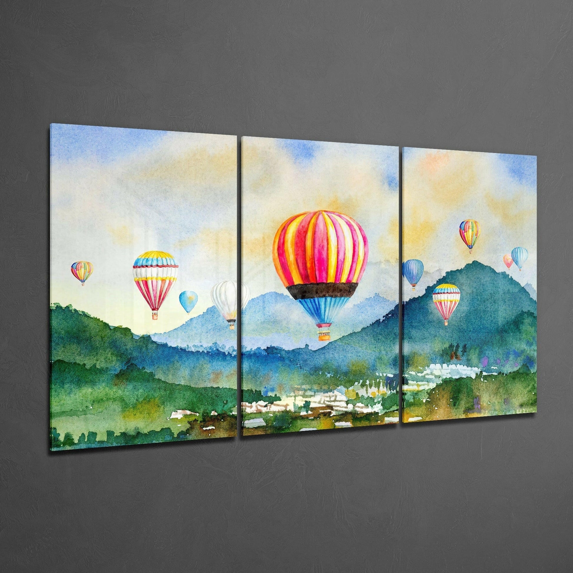 Three-panel glass art depicting colorful hot air balloons floating above green mountains and a valley town under a cloudy sky.