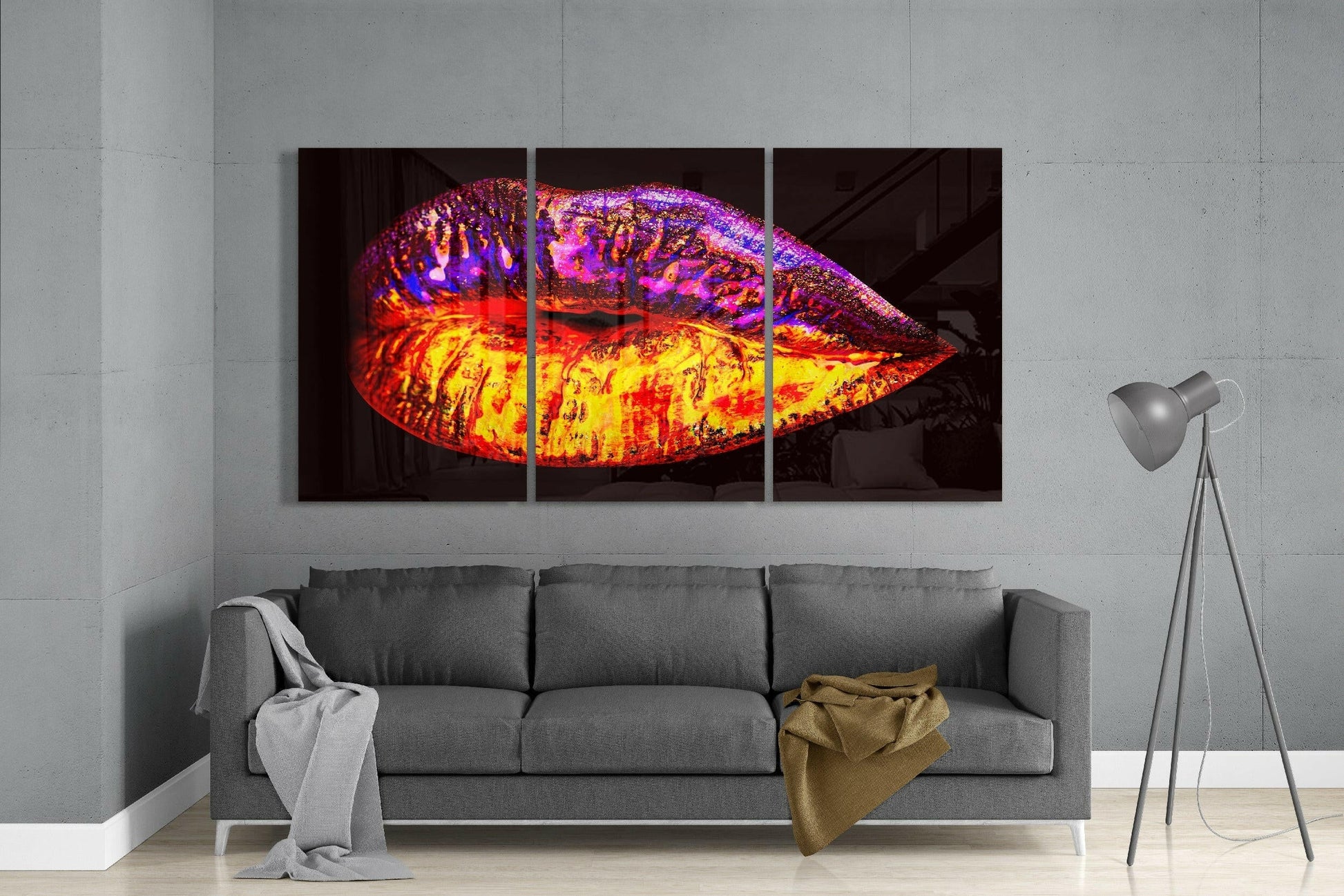 Vibrant neon glass lip sculpture with red, yellow, purple and blue colors displayed above gray sofa in modern living room.