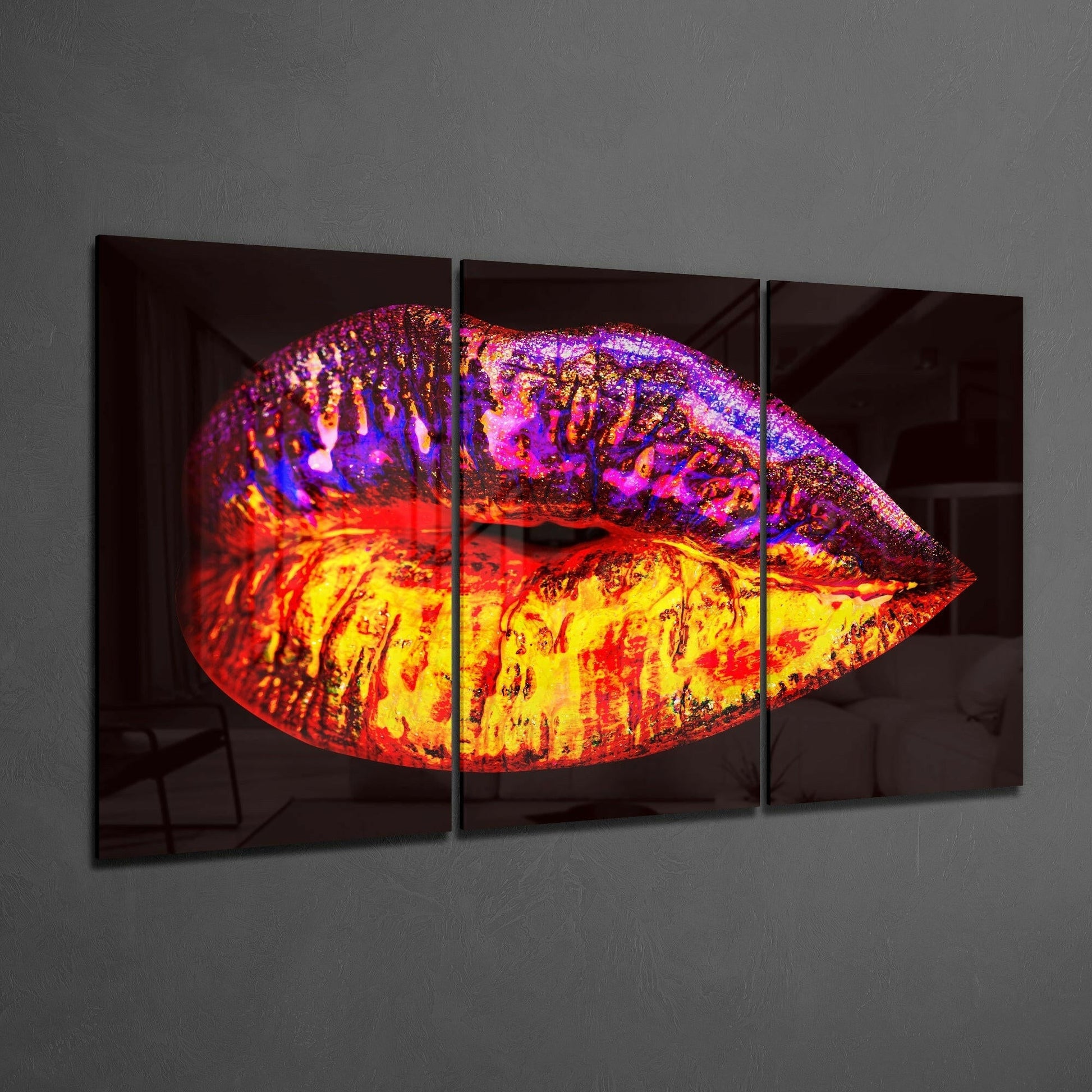 Three-panel glass art depicting a stylized lips design with vibrant gradient colors transitioning from yellow and red at center to purple and blue at edges, mounted horizontally on gray wall.