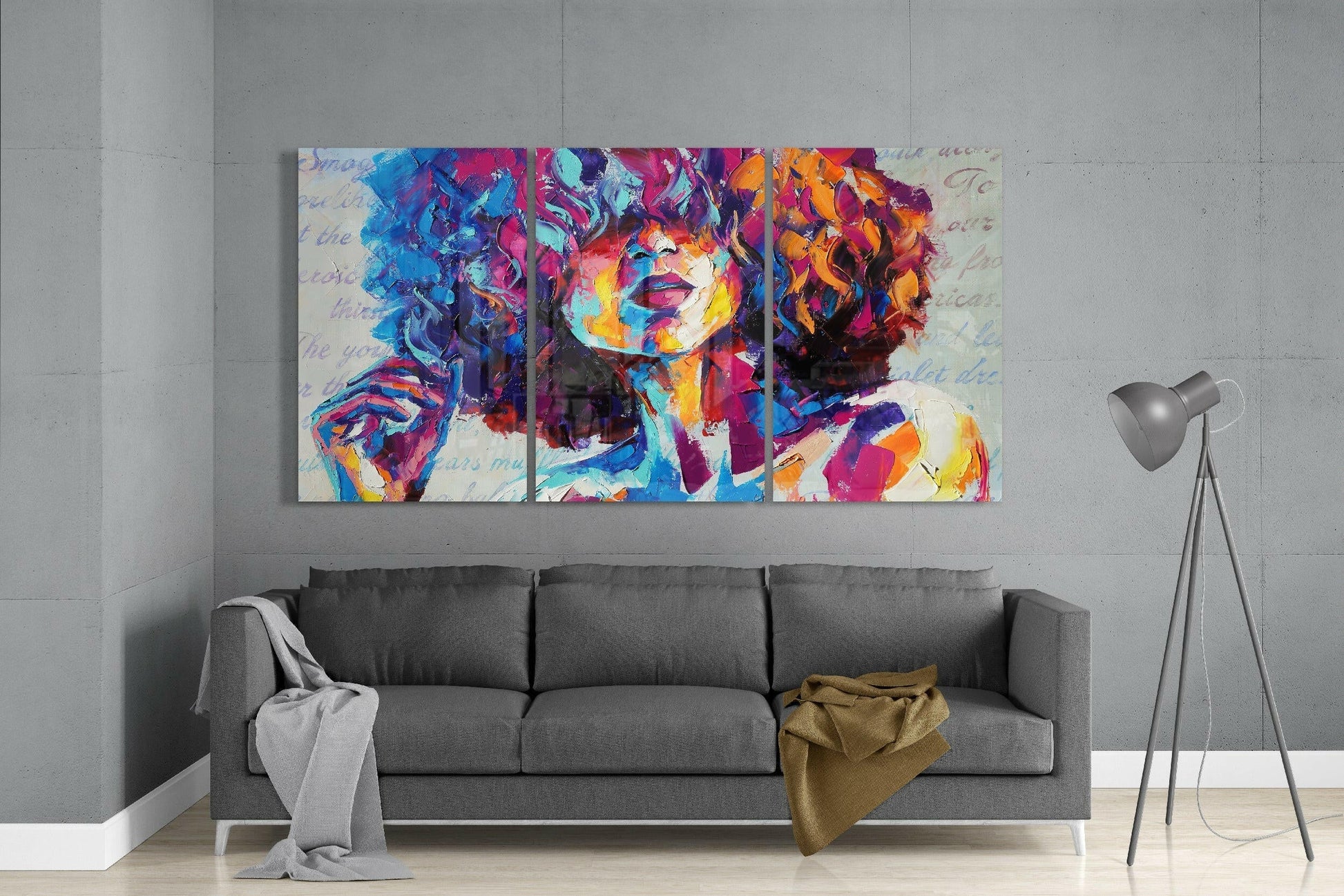 Colorful three-panel glass art depicting a portrait with vibrant blue, pink, orange, and purple tones, displayed above a gray sofa in a modern living room.