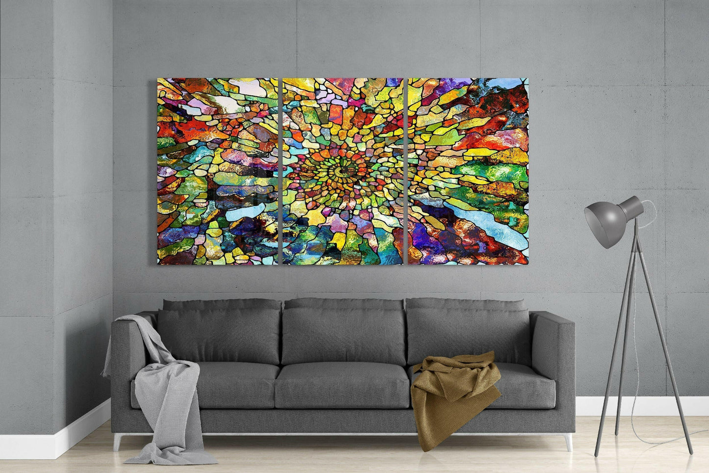 Three-panel vibrant stained glass art with radiating multicolored mosaic pattern displayed above gray sofa in modern living room.
