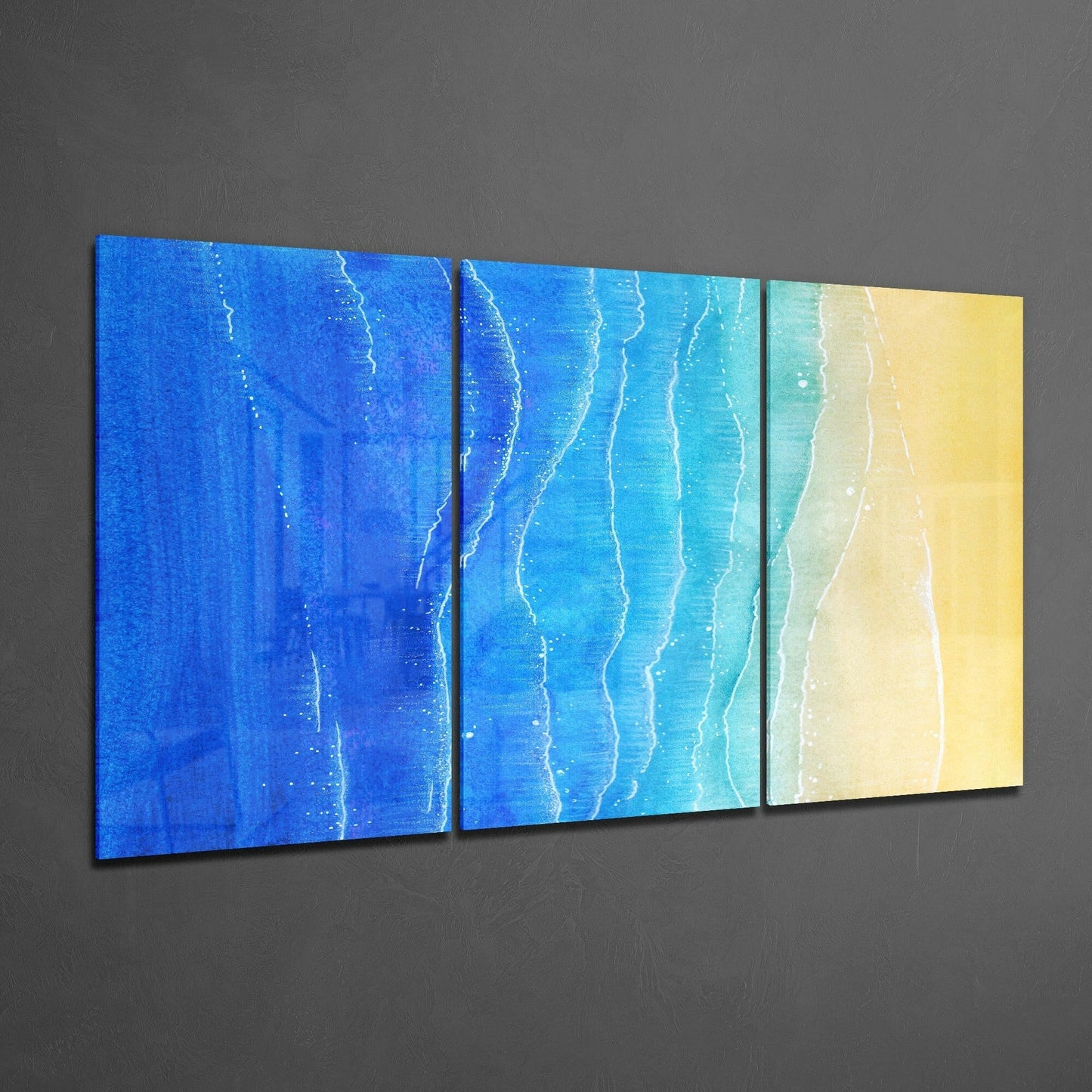 Three-panel beach glass art canvas displayed at an angle, showing gradient from deep blue ocean through turquoise to sandy yellow shore.