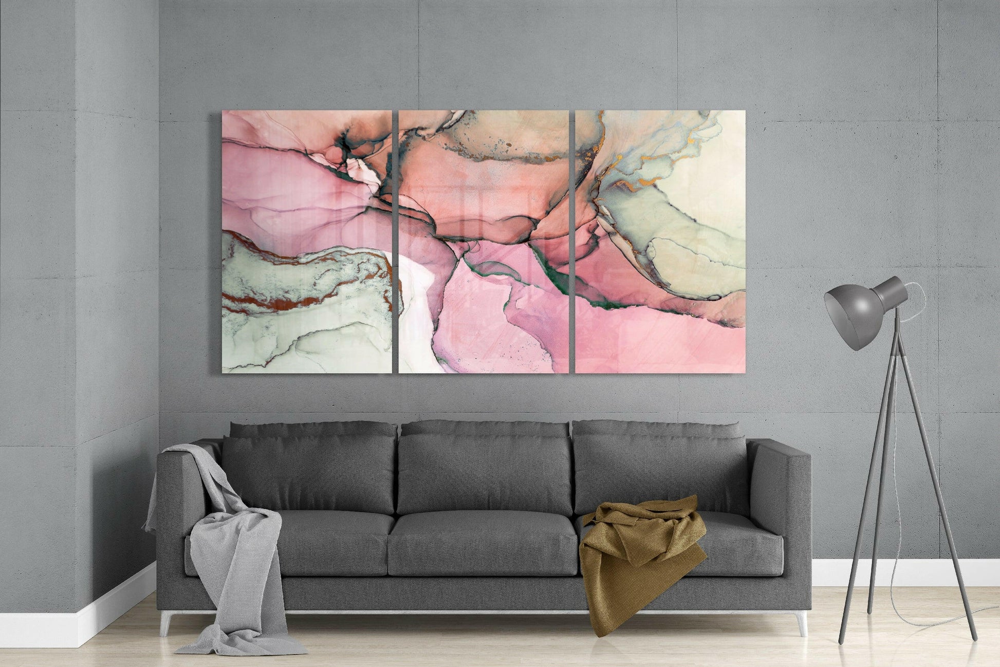 Three-panel pink and cream marble-effect glass art displayed above gray sofa in modern living room.