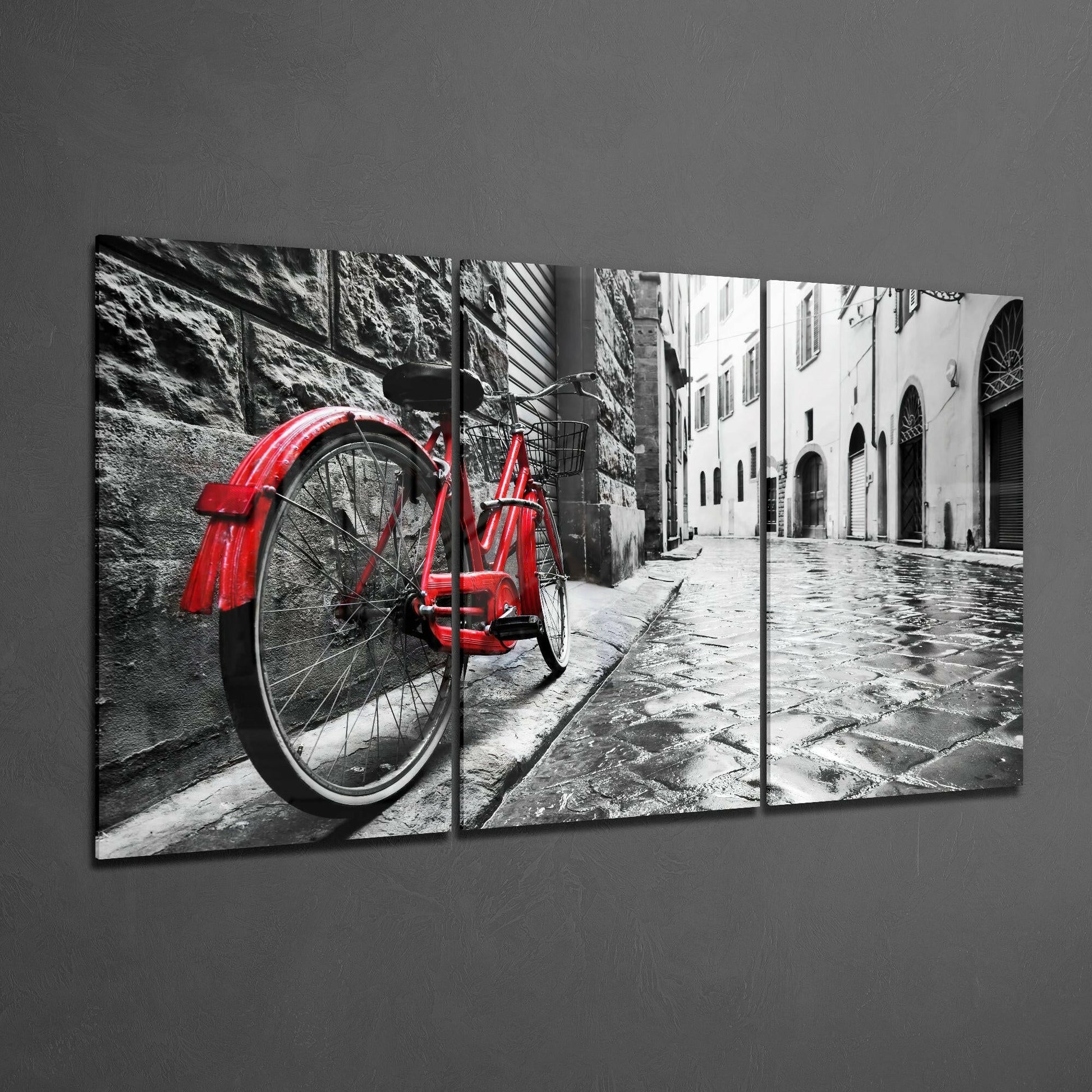 Three-panel glass art displaying a red vintage bicycle against monochrome European architecture and wet cobblestone street.
