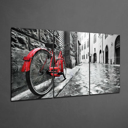 Three-panel glass art displaying a red vintage bicycle against monochrome European architecture and wet cobblestone street.