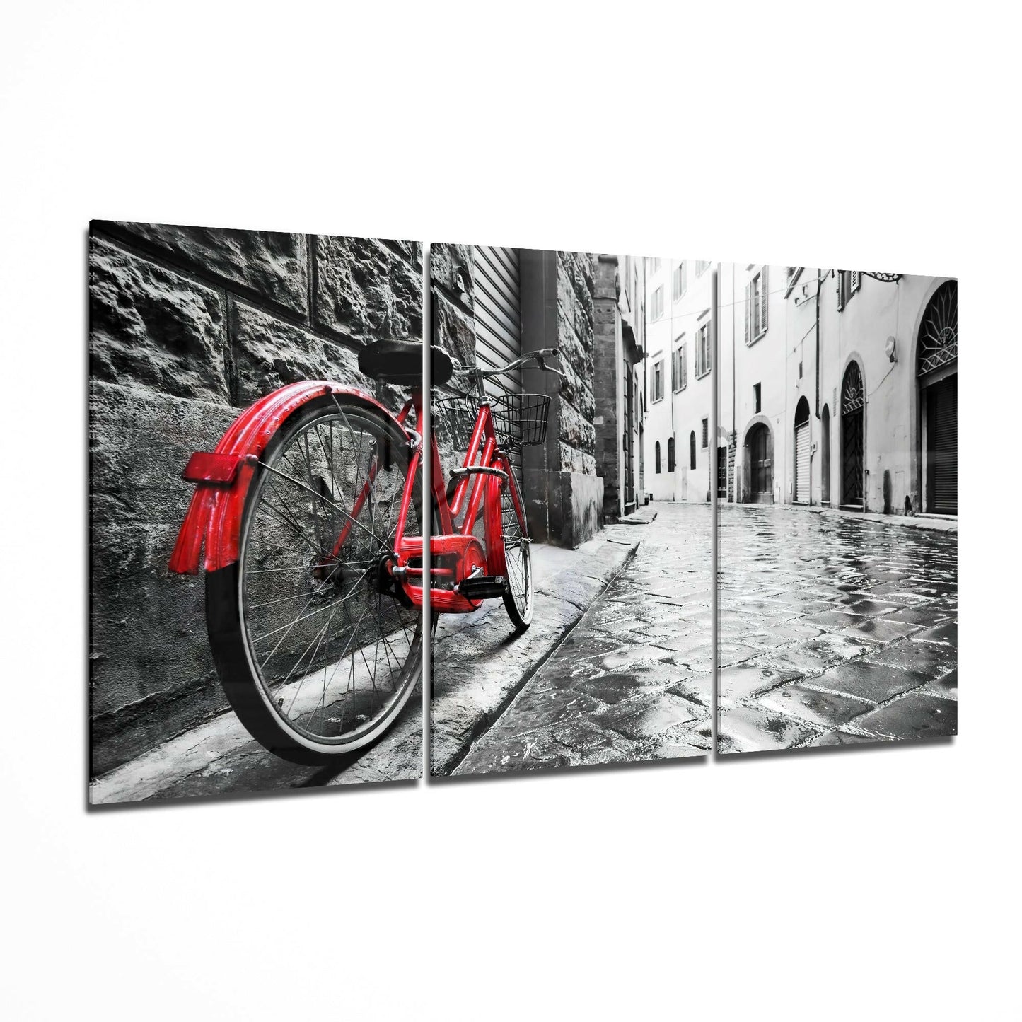Red vintage bicycle leaning against wet cobblestone street with historic European buildings in black and white background.