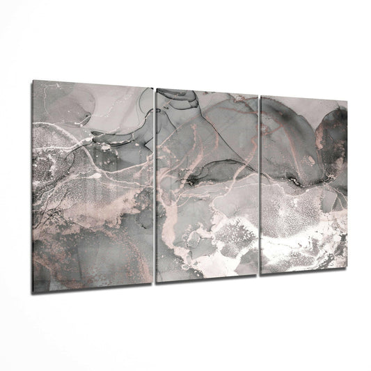 Three-panel gray glass art displaying abstract aerial landscape with white, pink, and dark gray tones and organic flowing patterns.