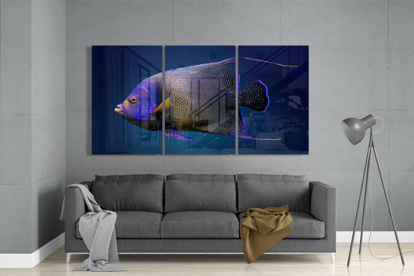 Three-panel glass art depicting a colorful angel fish with purple, yellow, and black markings displayed above a gray sofa in a modern living room.