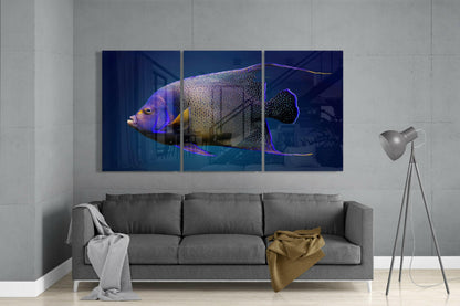 Three-panel glass art depicting a colorful angel fish with purple, yellow, and black markings displayed above a gray sofa in a modern living room.