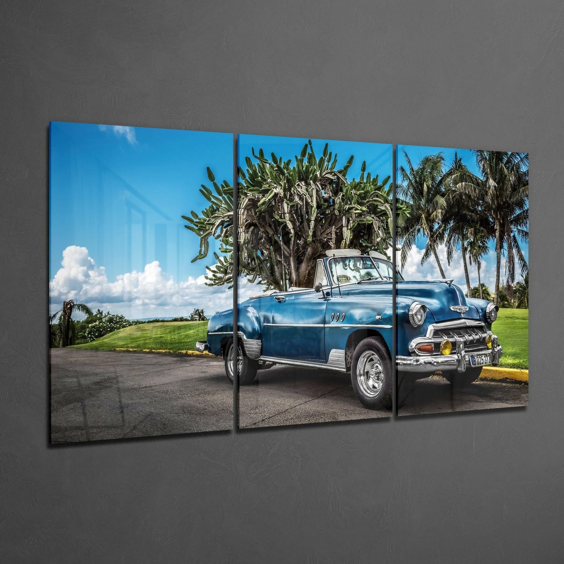 Three-panel glass art displaying a vintage blue convertible car parked beneath palm trees against a tropical landscape.