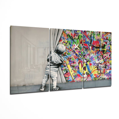 Three-panel glass wall art showing a child pulling back curtains to reveal vibrant multicolored graffiti street art behind.