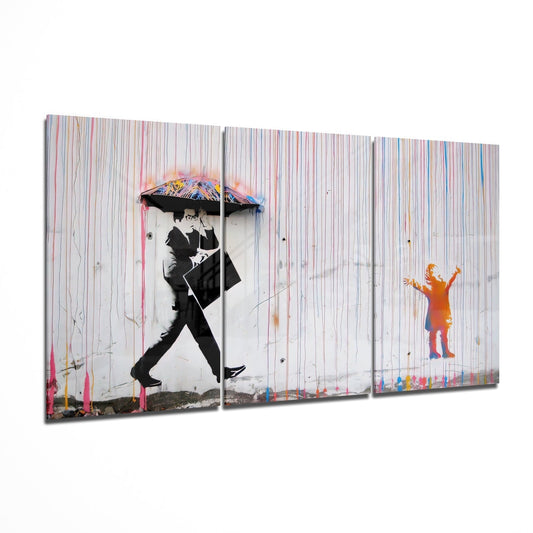 Three-panel glass wall art showing stylized figures with umbrellas and rain streaks against a striped background in black, white, and colorful accents.
