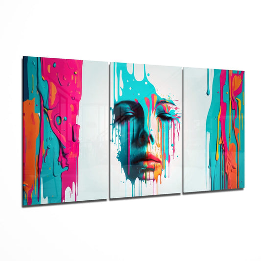 Three-panel triptych glass wall art displaying colorful abstract portrait with magenta, teal, and orange dripping paint effects on white background.