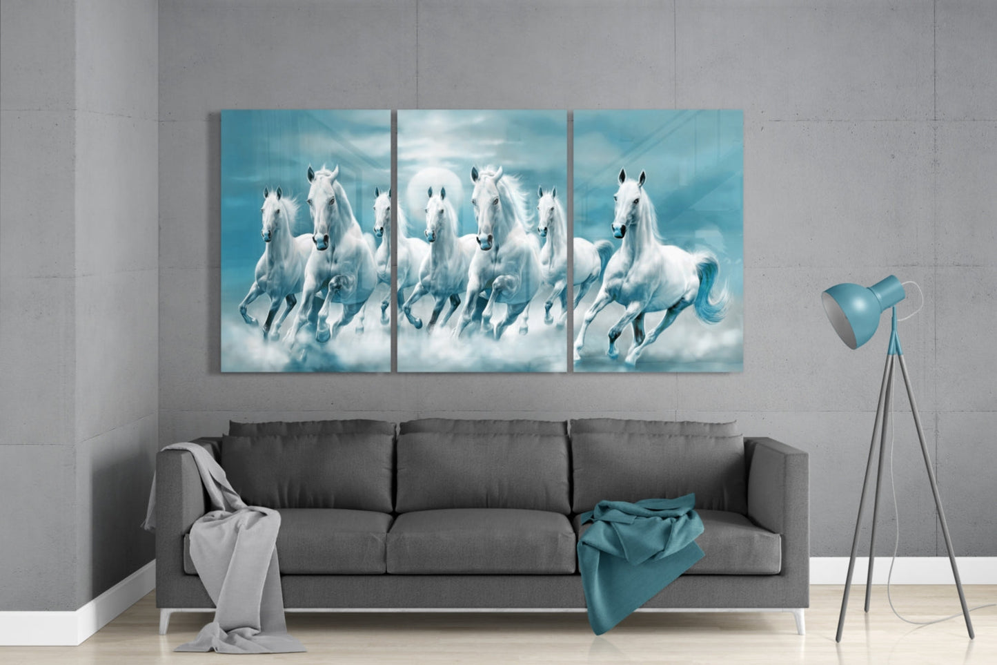 Three-panel glass wall art displaying white horses galloping through clouds against a turquoise sky, installed above a gray sofa in a modern living room.