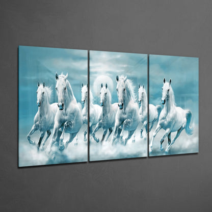 Three-panel teal glass wall art displaying white horses galloping through clouds against a blue sky, mounted on a gray wall.