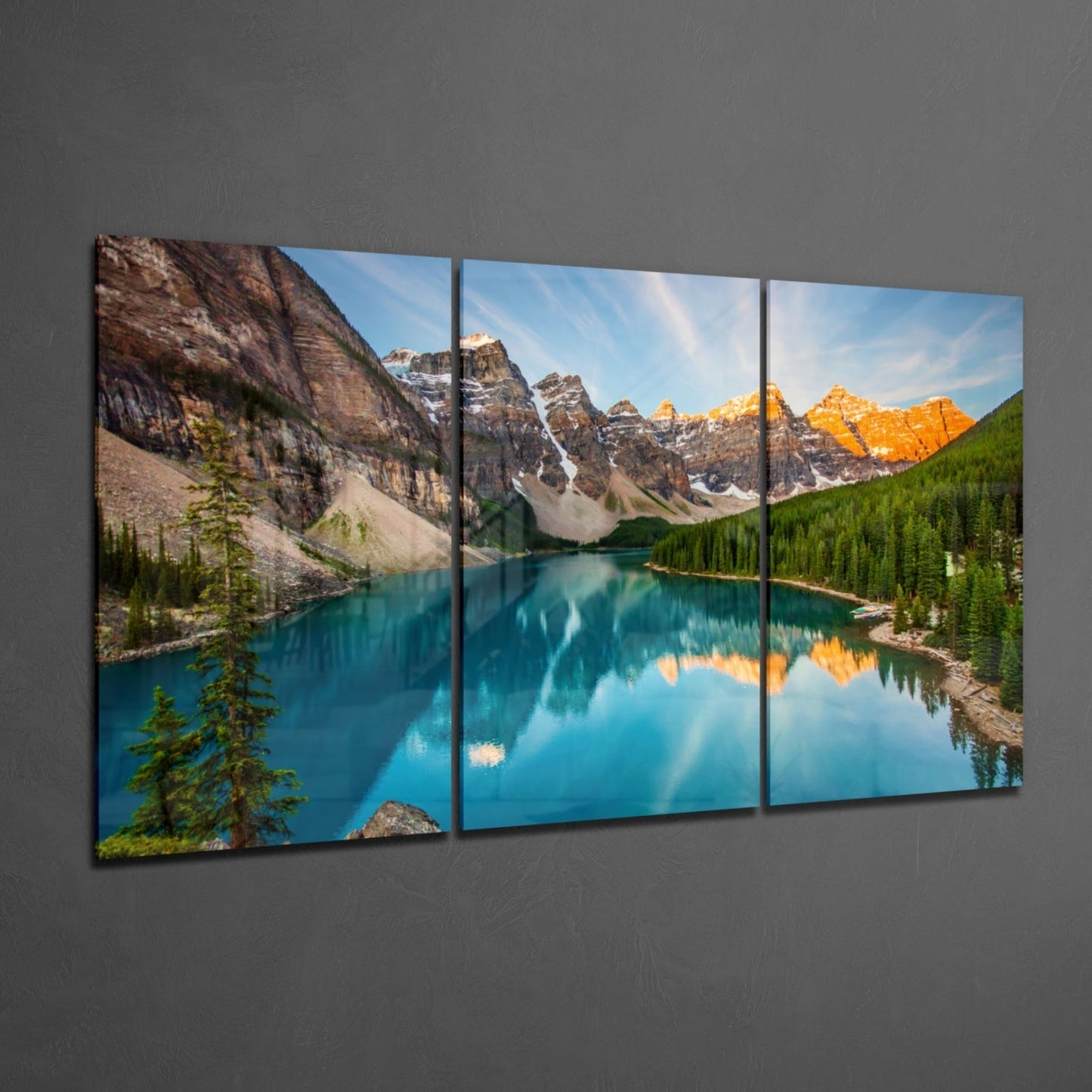 Three-panel glass wall art displaying a turquoise alpine lake surrounded by snow-capped mountains and evergreen forests under blue sky.