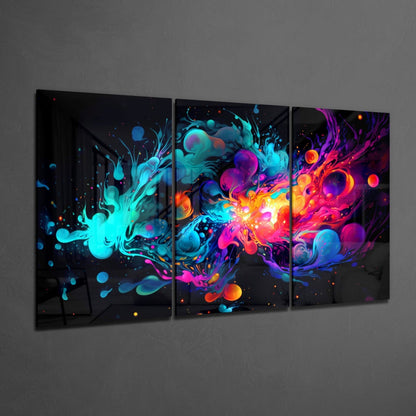 Three-panel glass wall art displaying vibrant neon cyan, magenta, orange, and blue liquid splashes against black background mounted on gray wall.