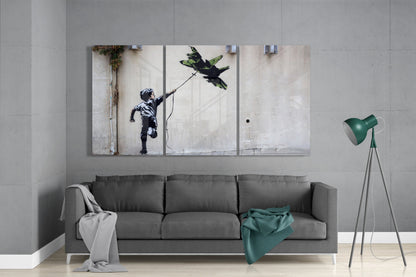 Multi-panel glass wall art depicting a child with a kite displayed above a gray sofa in a modern living room interior.