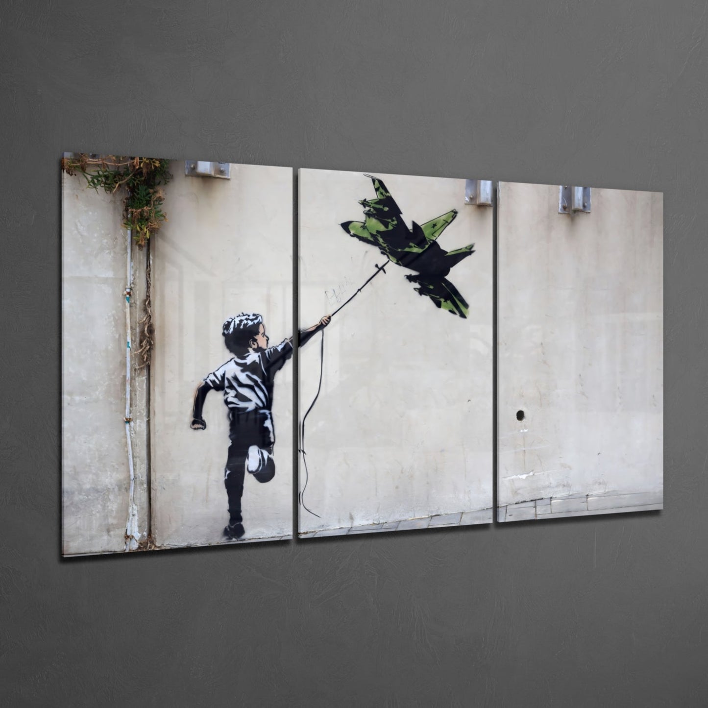 Multi-panel glass wall art displaying Banksy-style stenciled child reaching toward green bird on beige wall background.