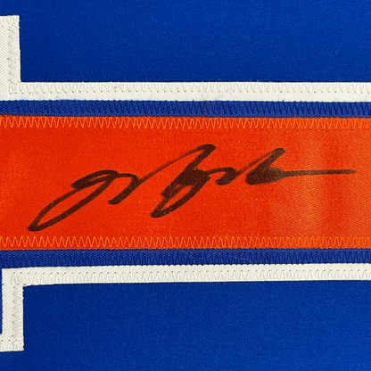 Close-up of striped jersey fabric showing blue, white, and orange horizontal stripes with black handwritten signature.