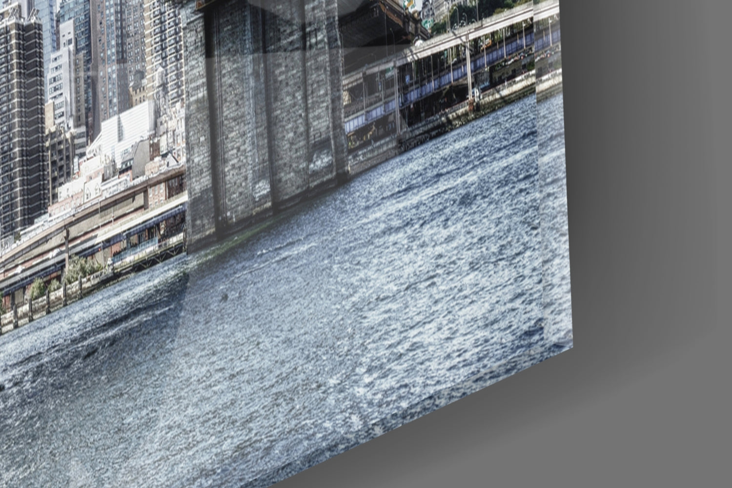 Angled view of glass wall art showing Manhattan waterfront with blue water, riverside buildings, and urban skyline in perspective.