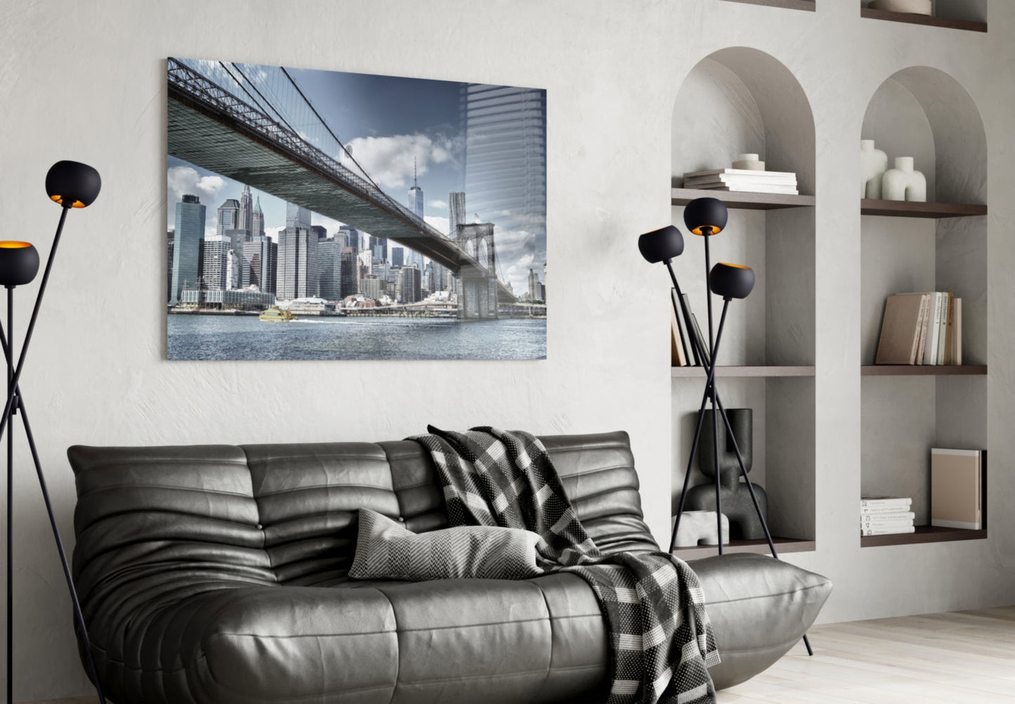 Manhattan Bridge glass wall art displaying NYC skyline and bridge over water, hung above black leather sofa in modern living room.