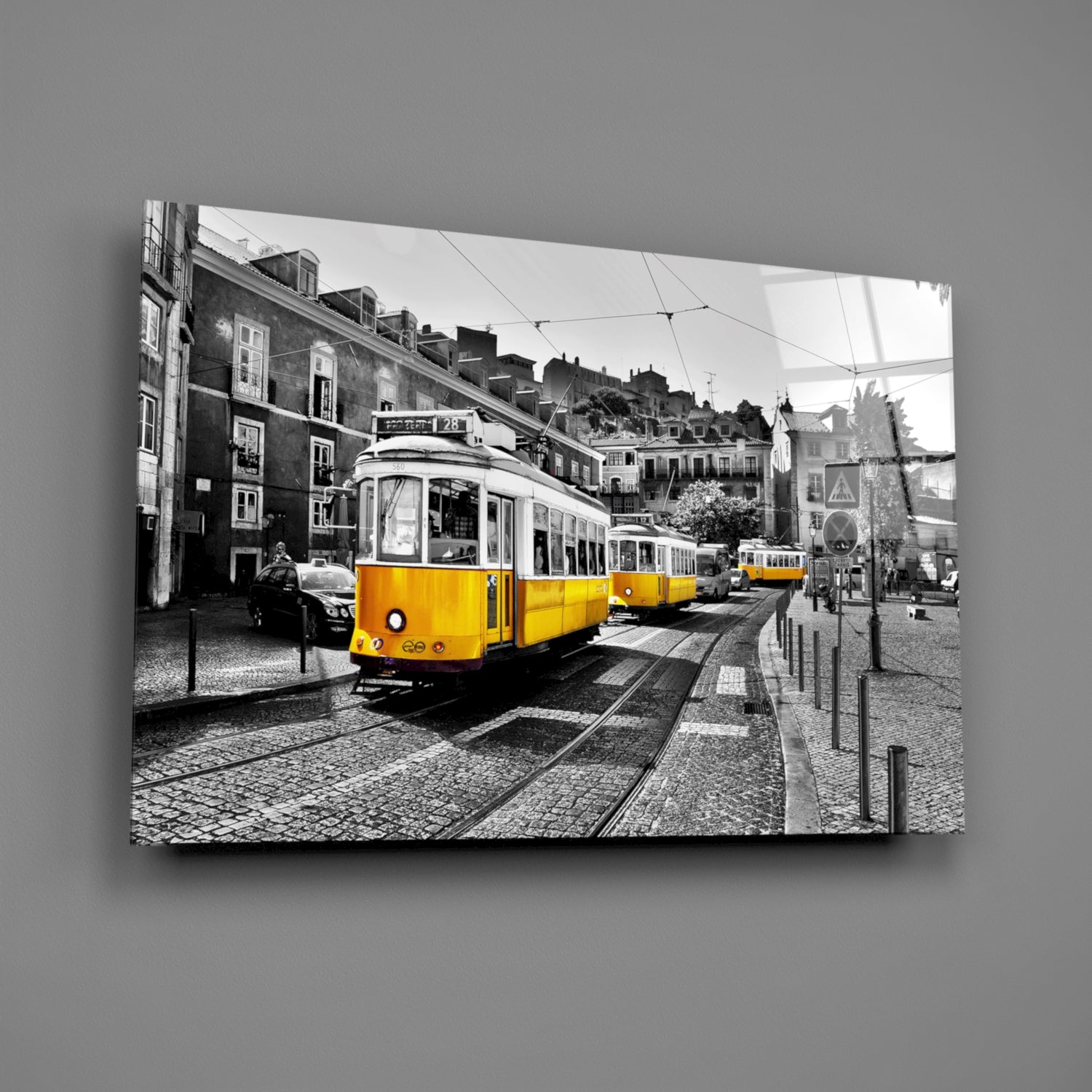 Yellow tram on cobblestone street with selective color against black and white cityscape of historic Lisbon buildings.