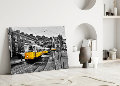 Yellow tram glass wall art leaning against white wall in minimalist room with neutral decor and sculptural objects.