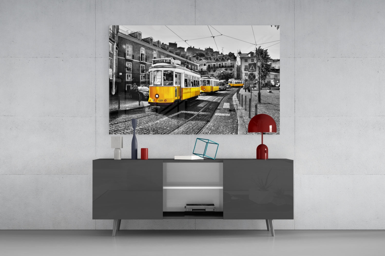 Yellow Tram glass wall art displayed above gray media console with red decorative objects in modern living room setting.