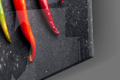 Close-up angled view of colorful chili peppers on dark textured glass surface against gray background.
