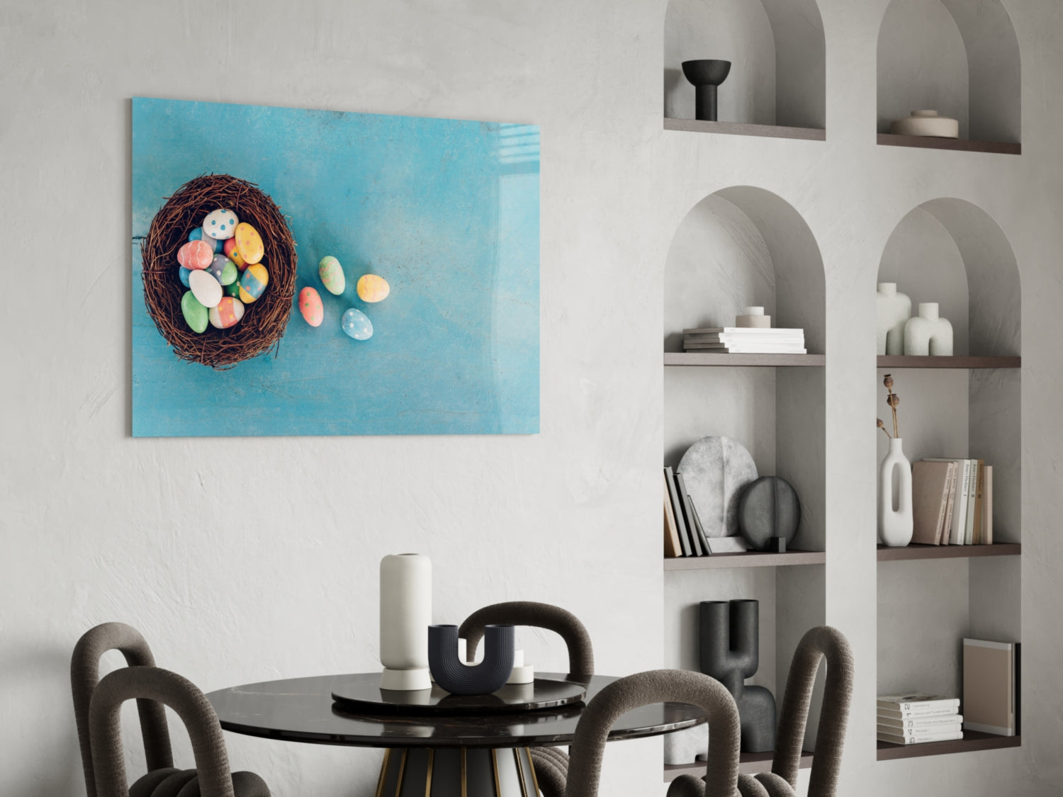 Turquoise glass wall art featuring a woven nest with colorful Easter eggs displayed above a black dining table in a modern interior setting.