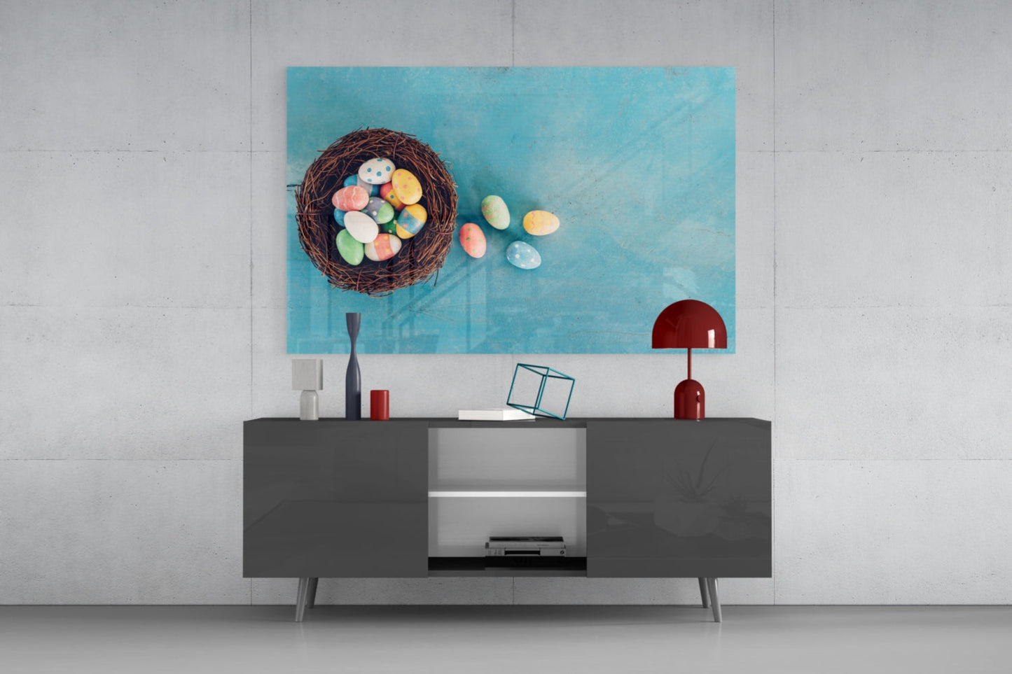 Turquoise glass wall art featuring a nest with colorful Easter eggs displayed above a modern gray media console in a minimalist interior setting.
