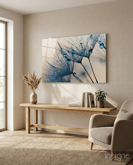 Blue dandelion water drops glass art displayed above wooden console table in minimalist beige living room with chair and window.