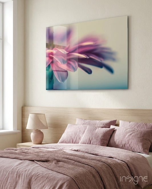 Soft pink gerbera glass wall art displayed above a wooden bed headboard in a minimalist bedroom.