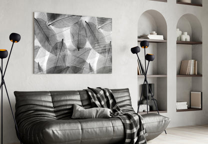 Black and white leaf-patterned glass art hanging above a gray leather sofa in a modern living room interior.