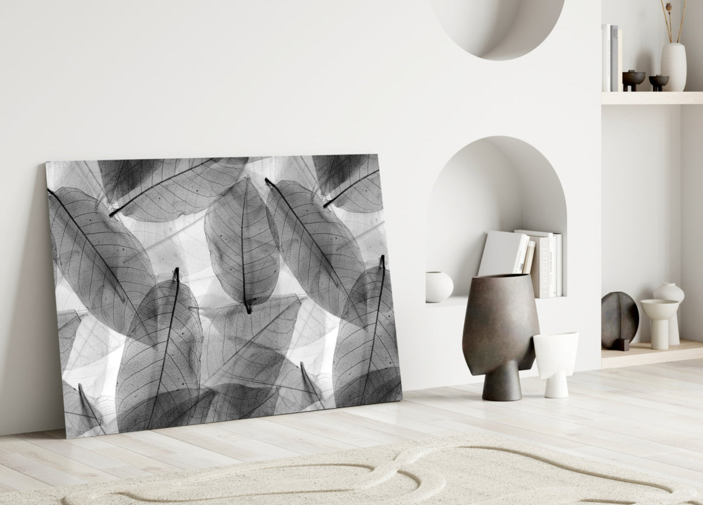 Black and white skeletal leaf pattern glass artwork displayed against white wall in minimalist interior setting.