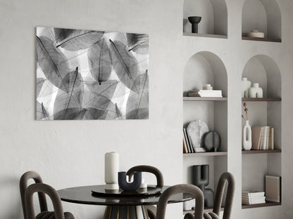 Black and white botanical leaf glass wall art displayed above a round black dining table with upholstered chairs and white shelving unit.