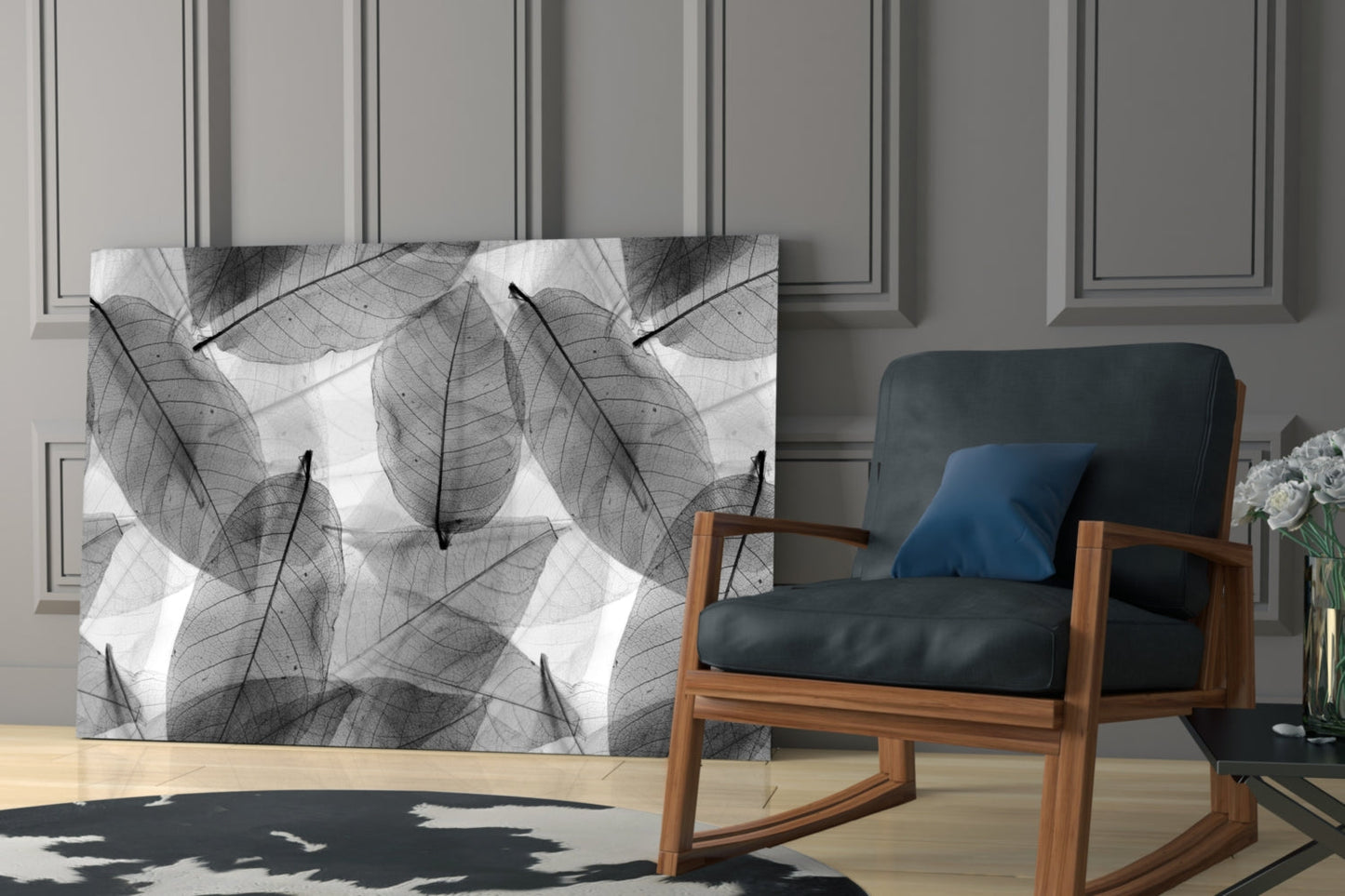 Black and white skeletal leaf pattern glass panel displayed on wall beside wooden chair with blue cushion in modern interior.