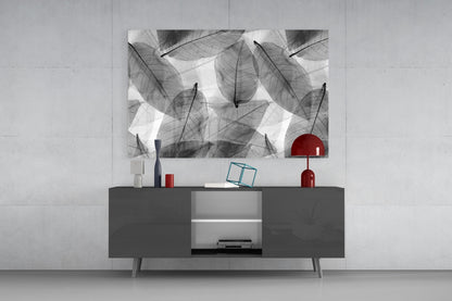Black and white leaf-patterned glass wall art displayed above a dark gray media console with red decorative accents.
