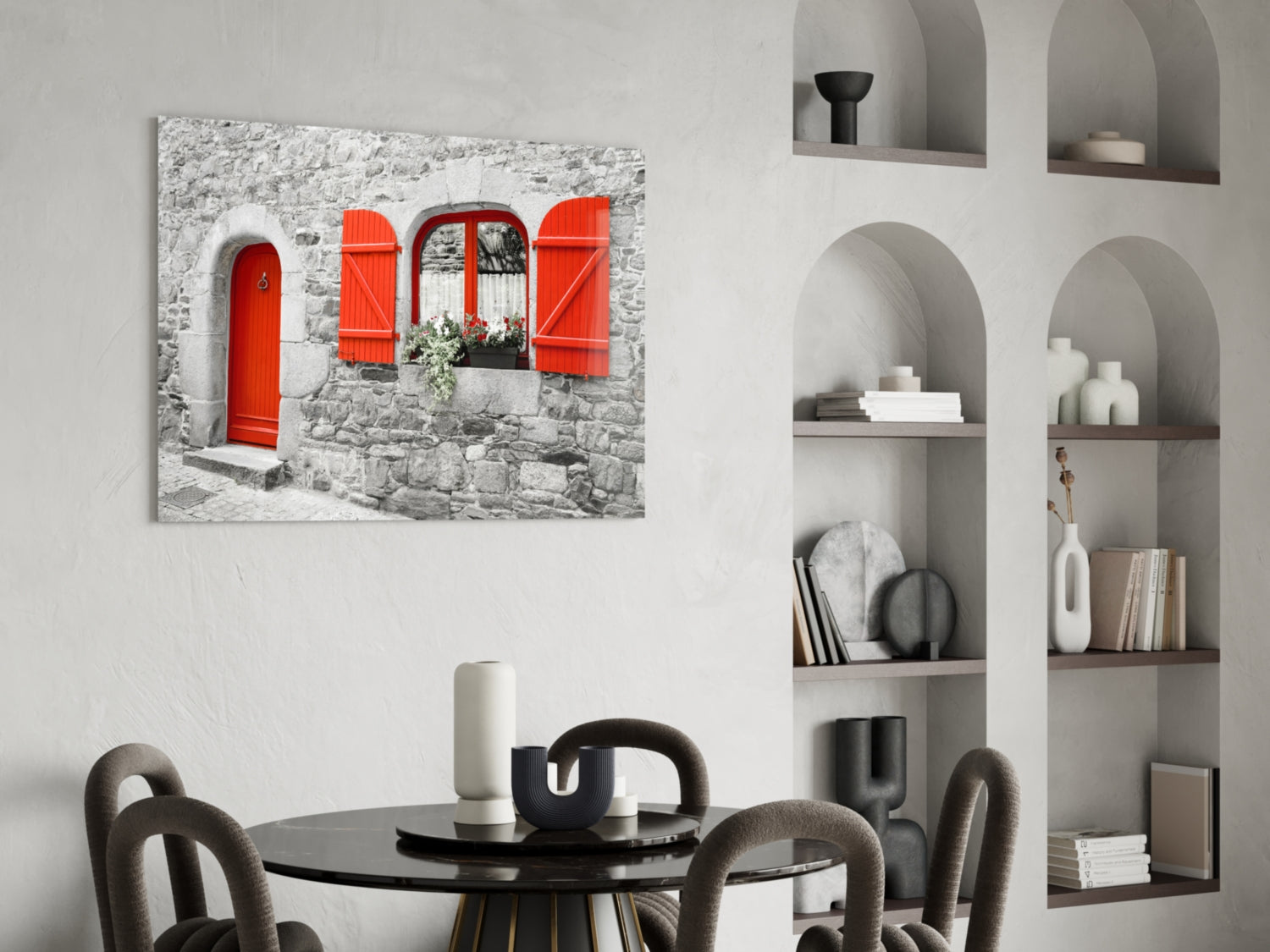Red door glass wall art displayed above a round black dining table with upholstered chairs in a modern interior with white shelving.