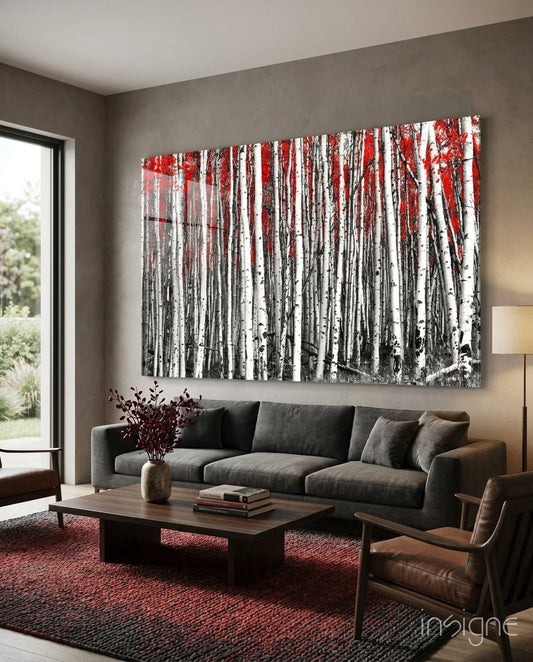 Large glass wall art depicting a black and white birch forest with red autumn foliage, displayed above a gray sofa in a modern living room.