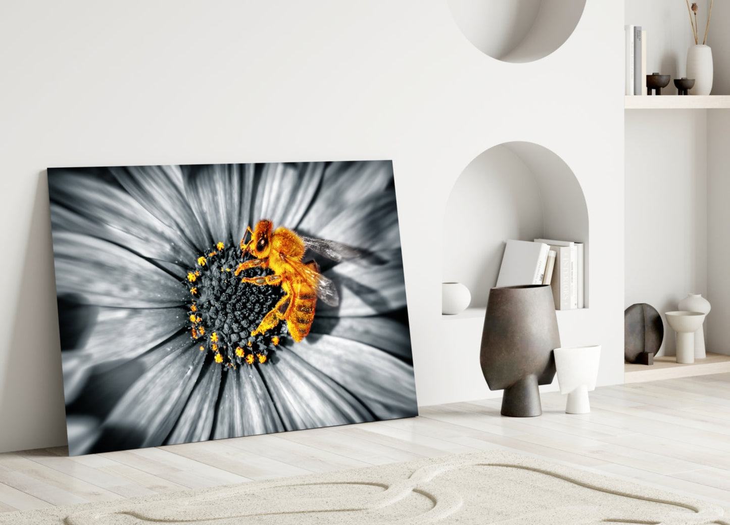 Honey Bee Glass Wall Art leaning against white wall in minimalist room, displaying bee on yellow flower with grayscale petals.