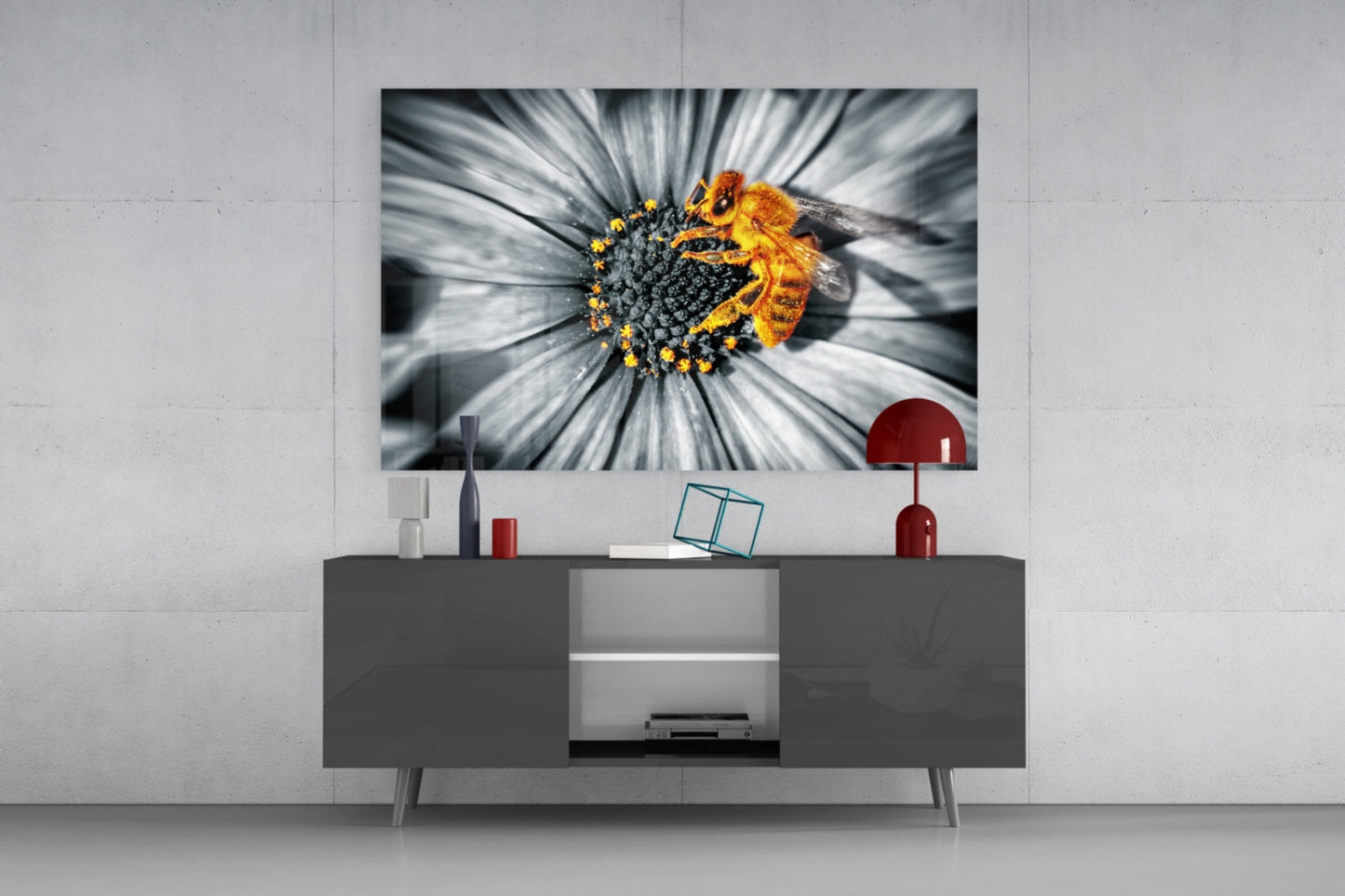 Honey bee glass wall art displayed above a dark gray media console, showing a bee on a white and gray daisy with yellow center against white wall.
