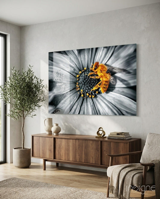 Honey bee glass wall art mounted above wooden credenza in modern living room with plant and chair visible.