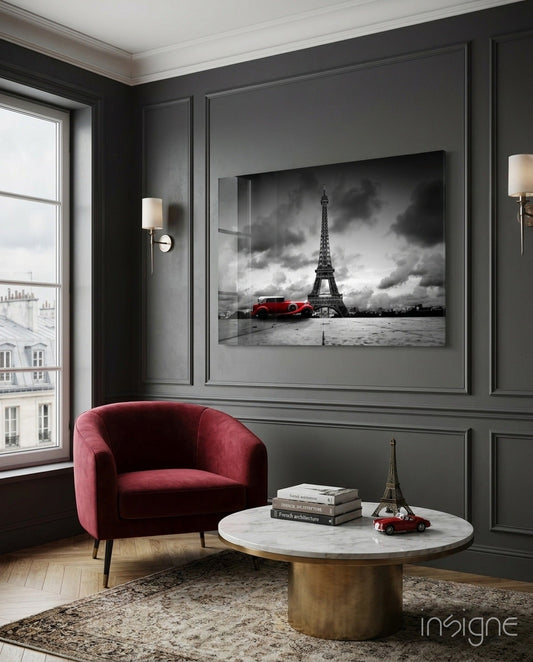 Red vintage car and Eiffel Tower black and white framed glass wall art displayed above marble table in modern gray paneled room.